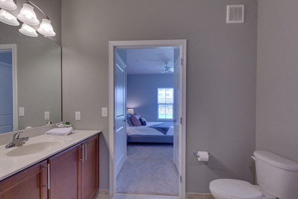 a bathroom with a toilet sink and a mirror and a bedroom