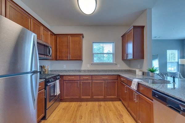 an empty kitchen with wooden cabinets and stainless steel appliances