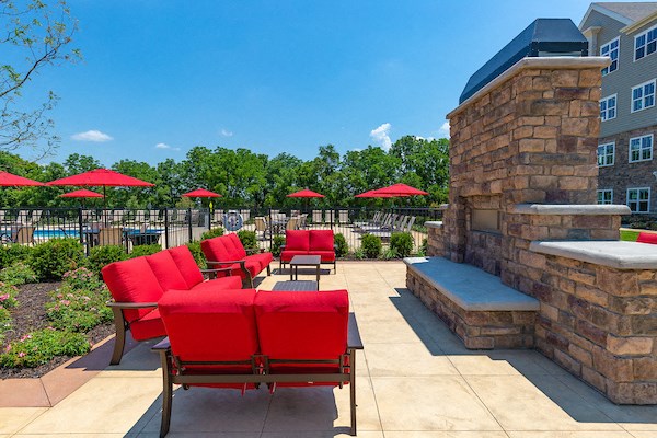 a patio with red chairs and umbrellas and a stone fireplace