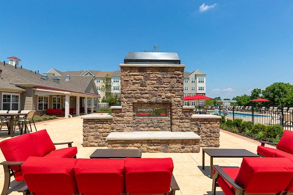 a clubhouse patio with a stone fireplace and red couches
