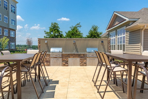 a patio with tables and chairs and a bar with a grill