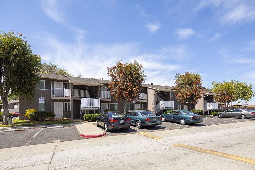 an apartment building with cars parked in a parking lot