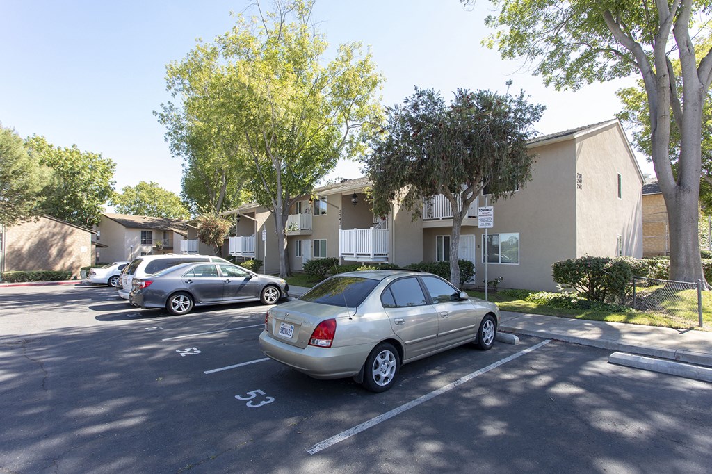 a parking lot with cars parked in front of apartment buildings