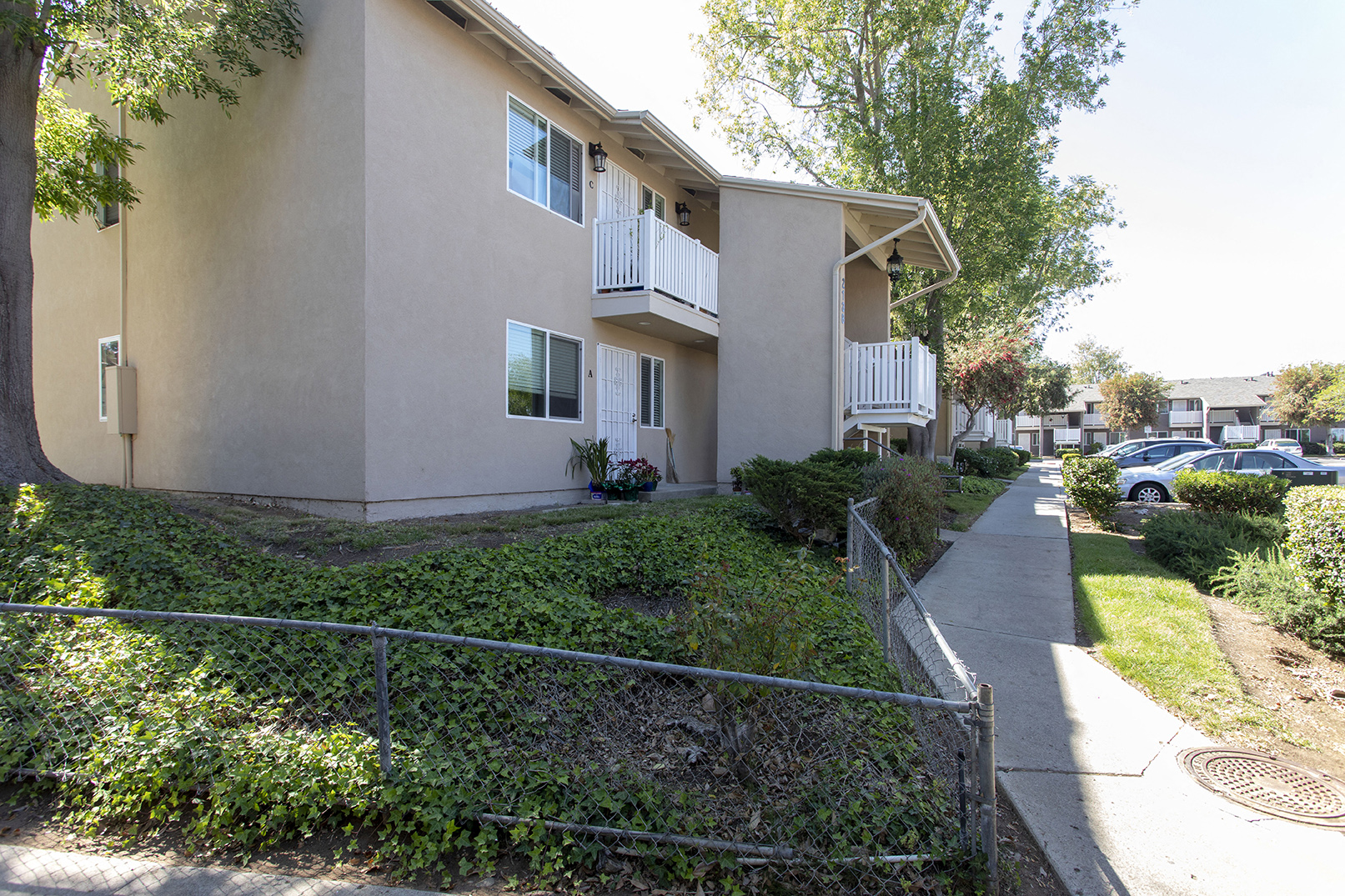 a white apartment building with a sidewalk in front of it