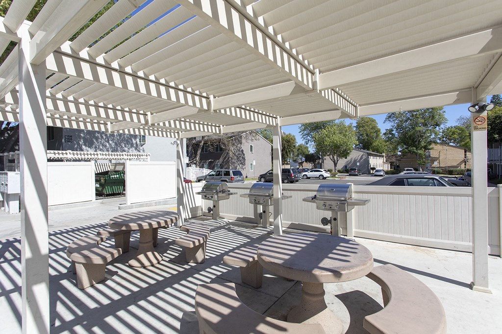 a covered patio with a picnic table and benches