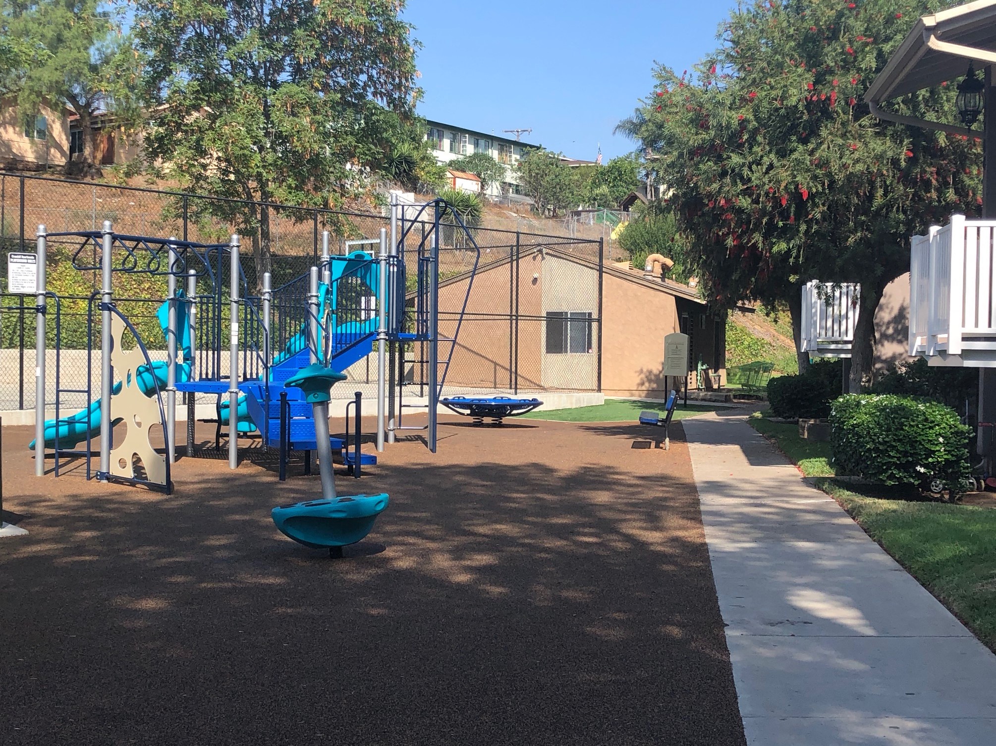 a playground with a swing set and slides in front of a house