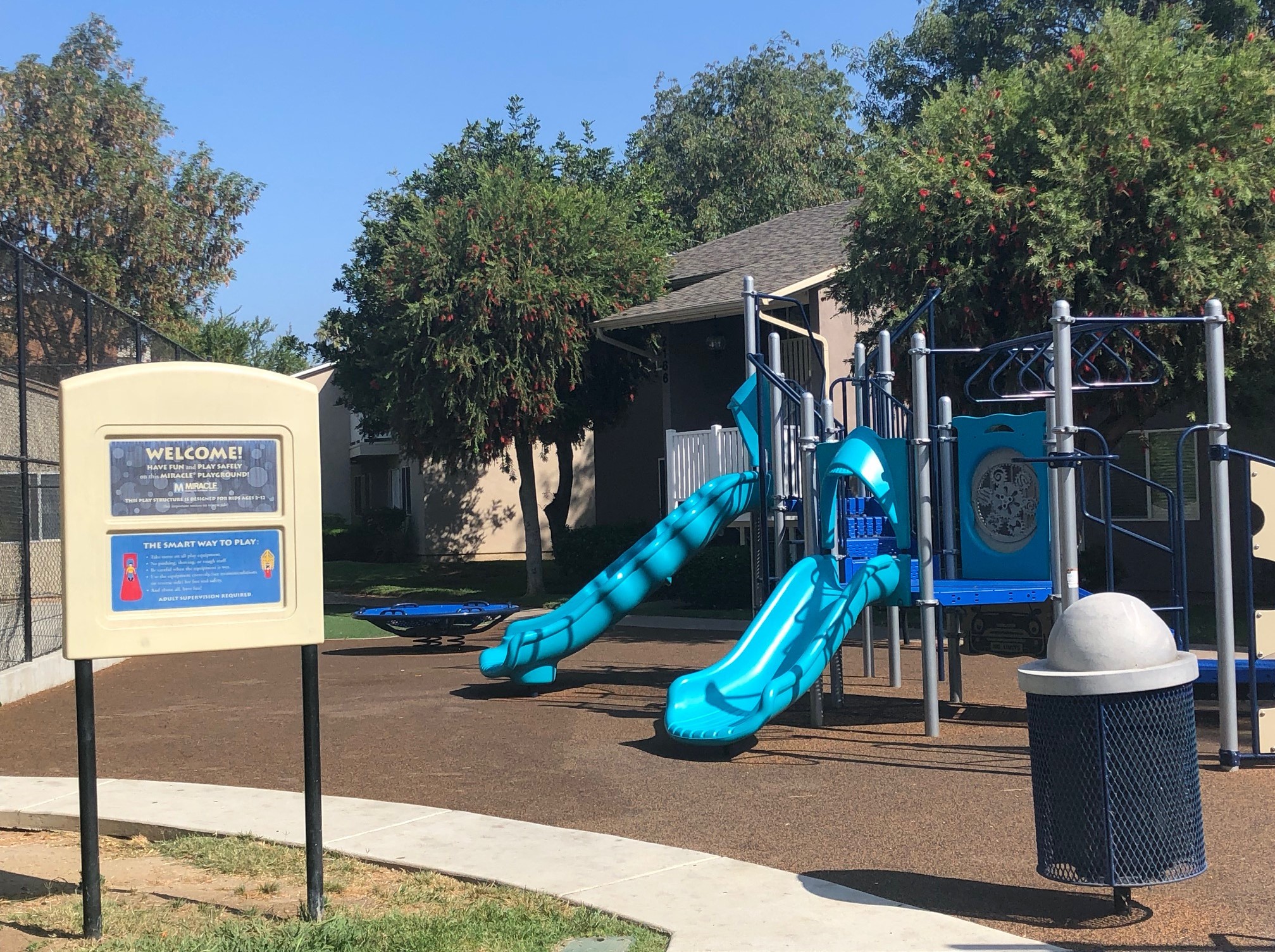 a playground with a blue slide and a sign