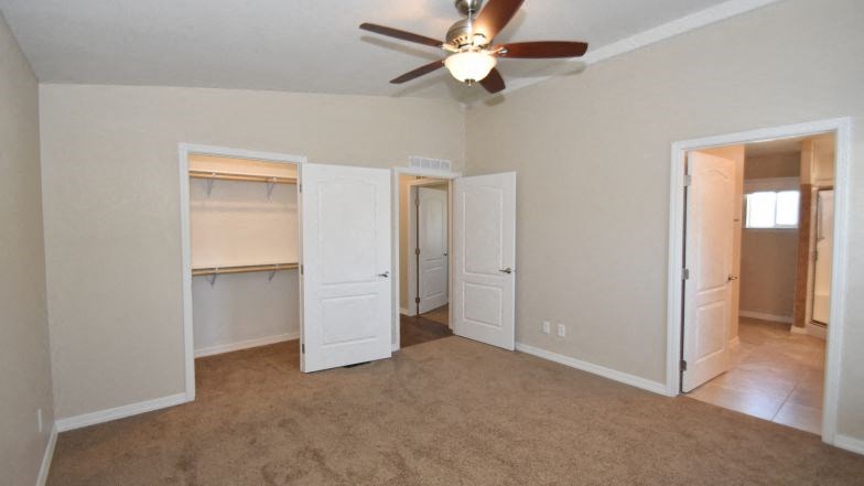 an empty living room with a ceiling fan and a closet