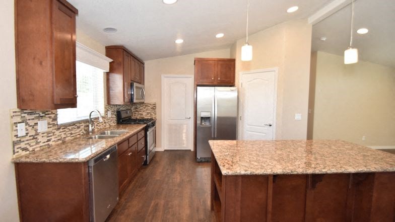 a kitchen with a marble counter top and a stainless steel refrigerator