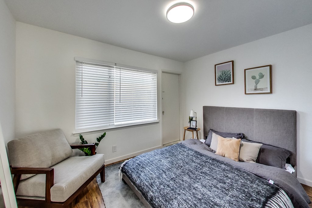 a bedroom with a bed and a chair and a window