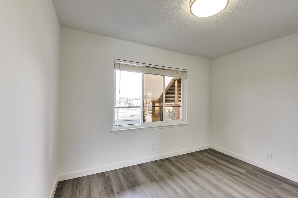 an empty living room with a window and wooden floors