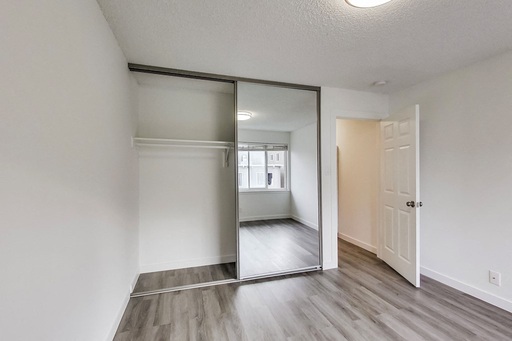 an empty bedroom with a mirror and a door to the bathroom