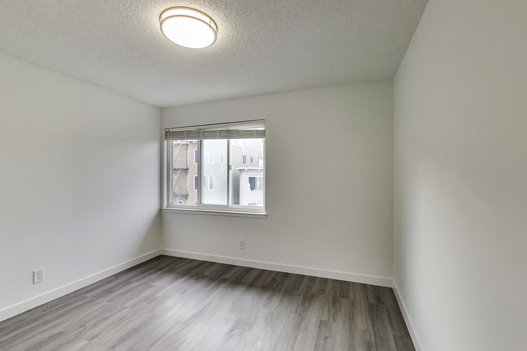 an empty living room with wood flooring and a window