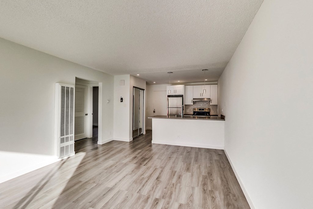 an empty living room and kitchen with wood flooring