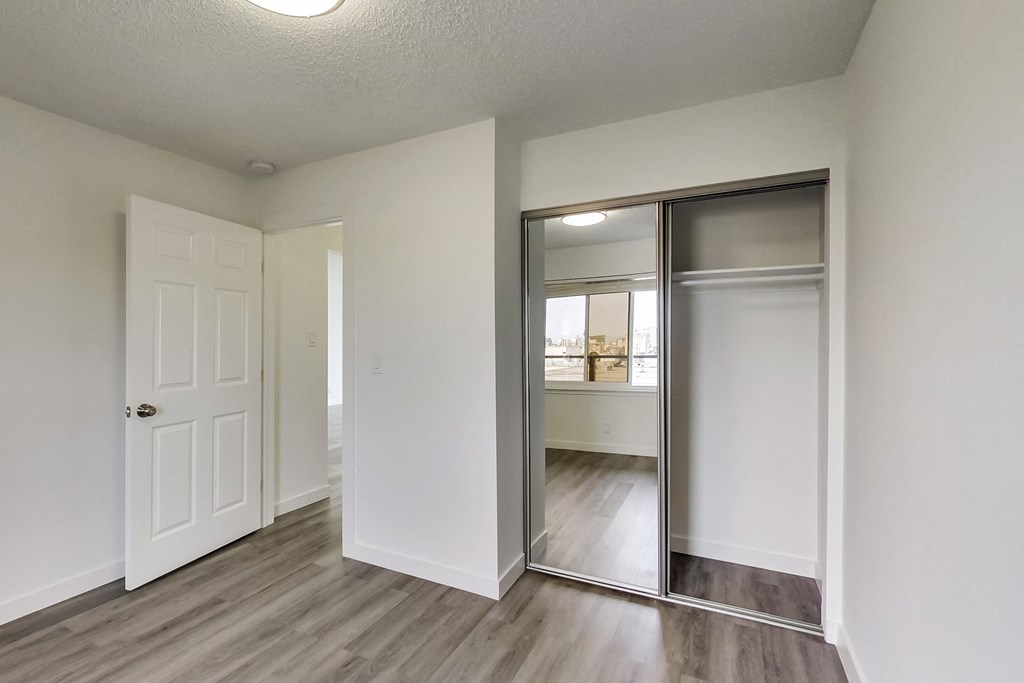 an empty bedroom with a mirrored closet door