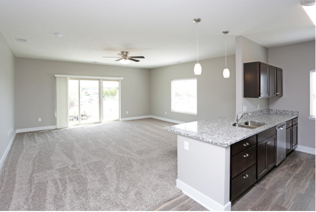 an empty kitchen and living room with a granite counter top
