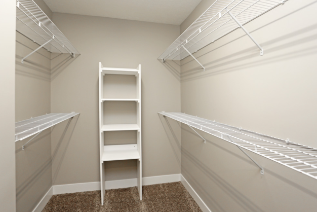 a spacious closet with two racks and a ladder in a closet