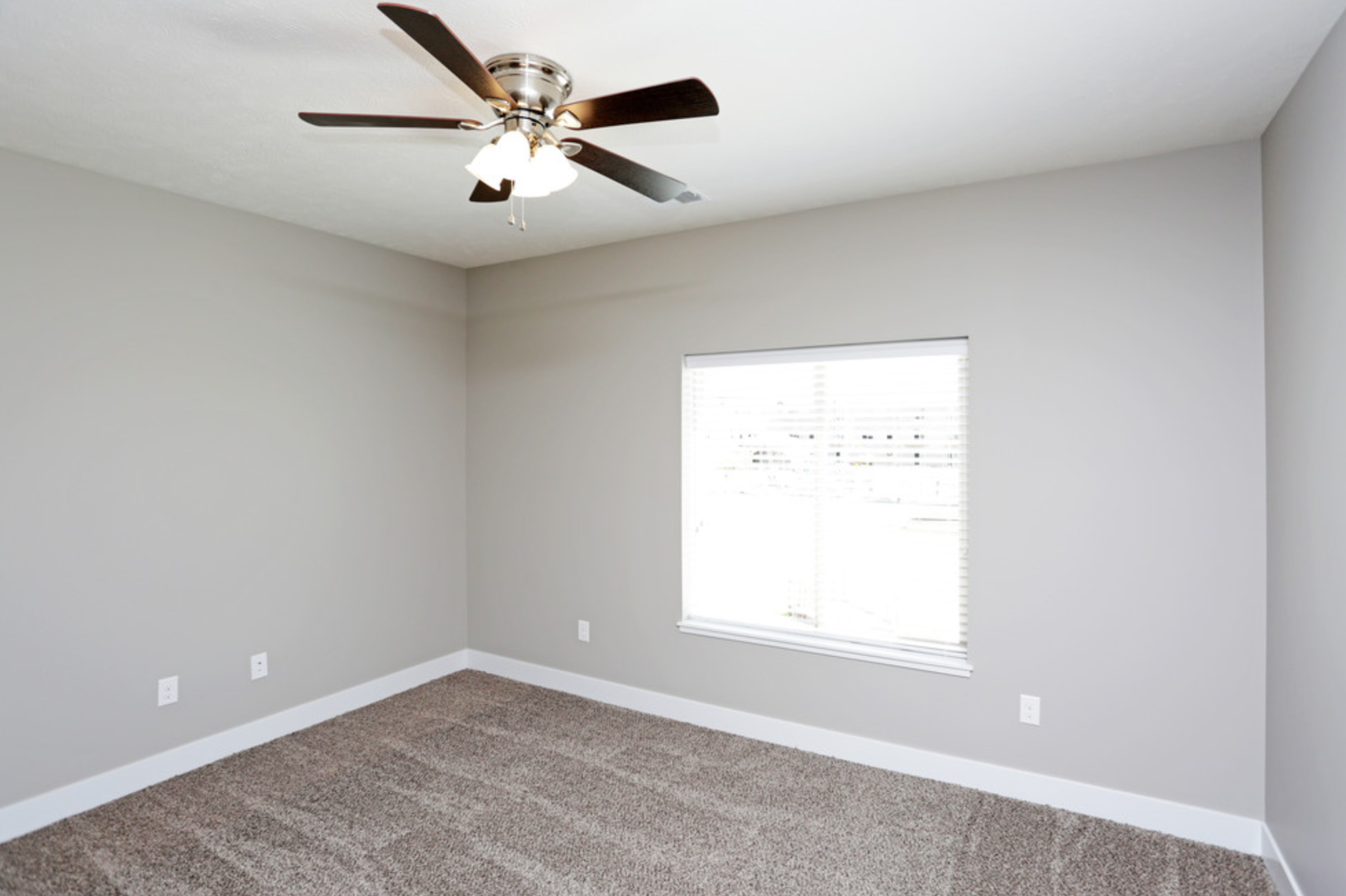 an empty room with a ceiling fan and a window