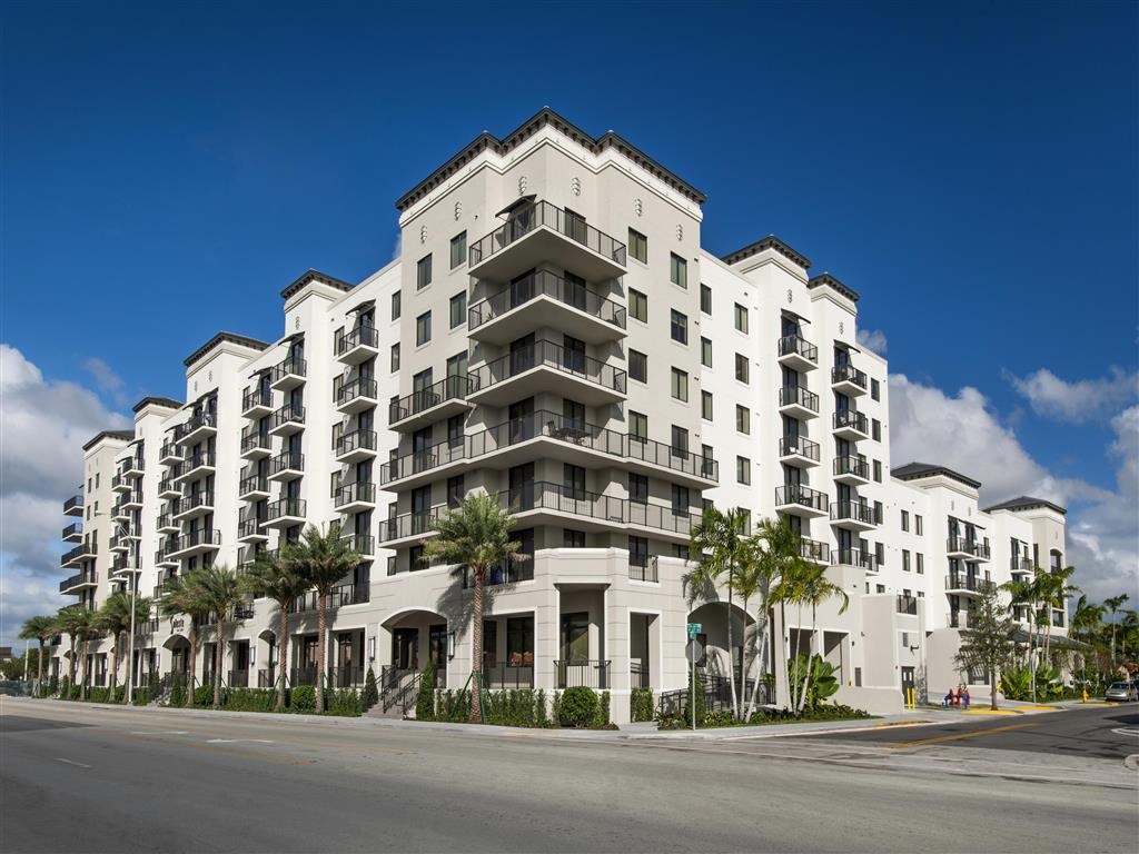 a large white building with palm trees on a street