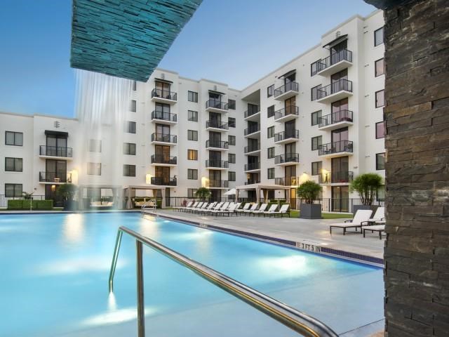a swimming pool with an apartment building in the background