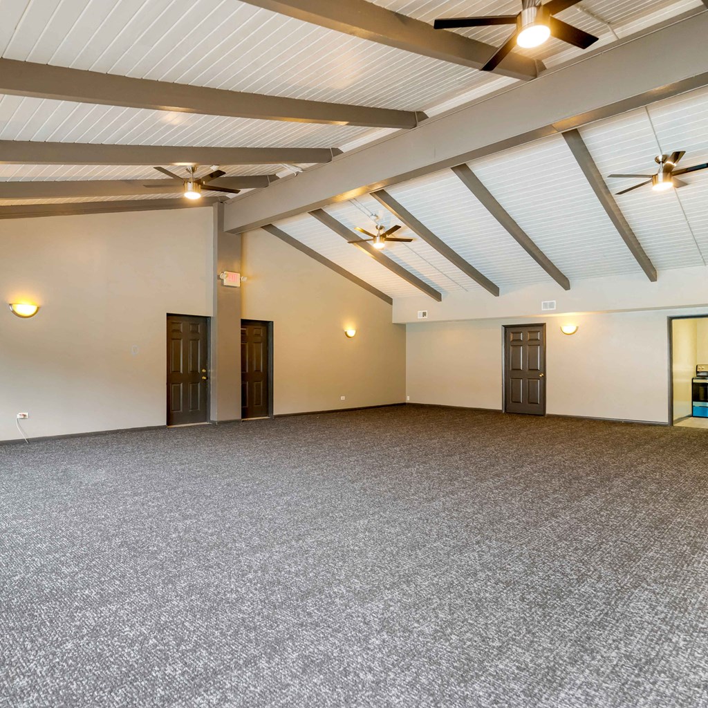 an empty room with ceiling fans and a carpeted floor