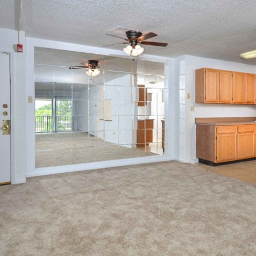 an empty living room with a ceiling fan and