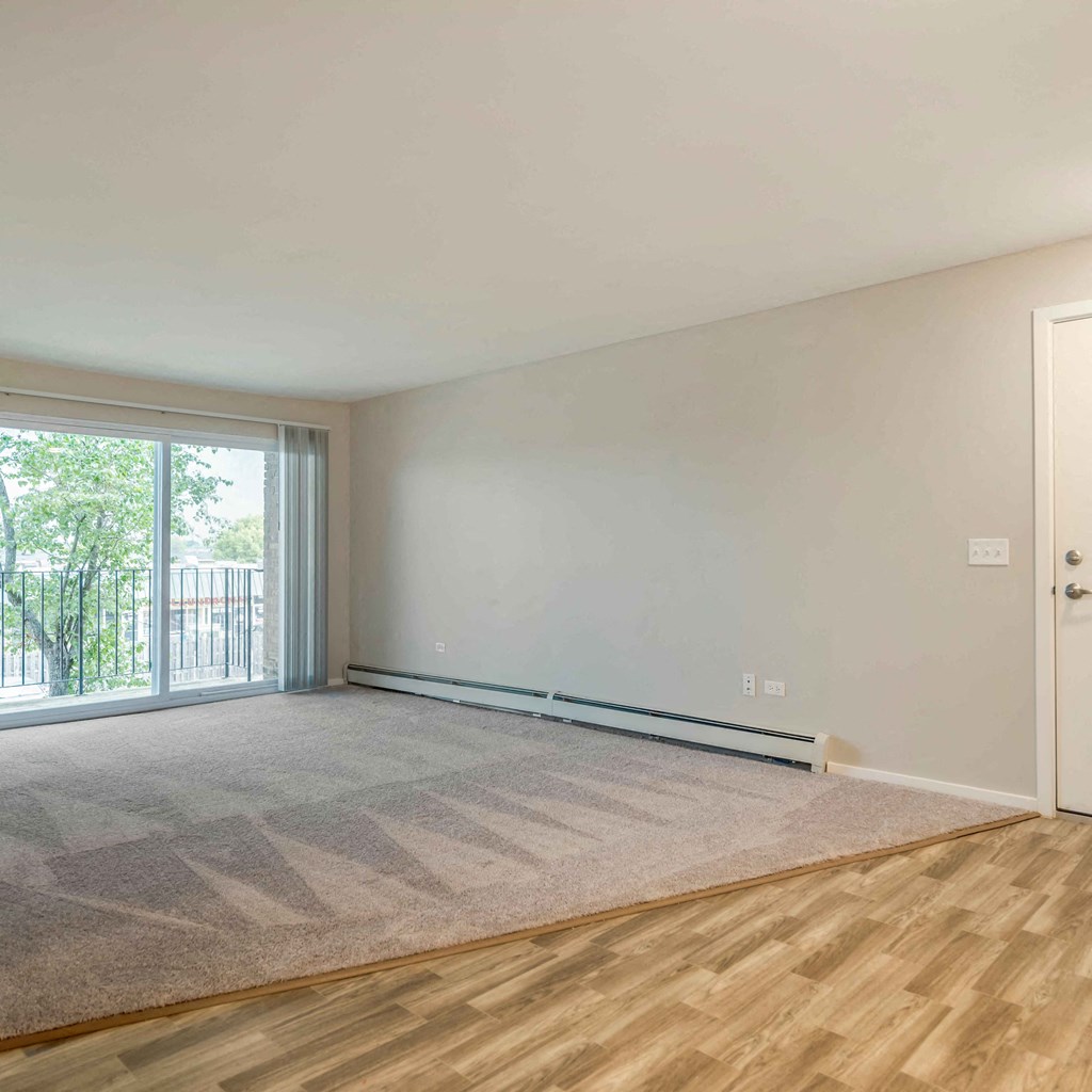 an empty living room with a sliding glass door to a balcony