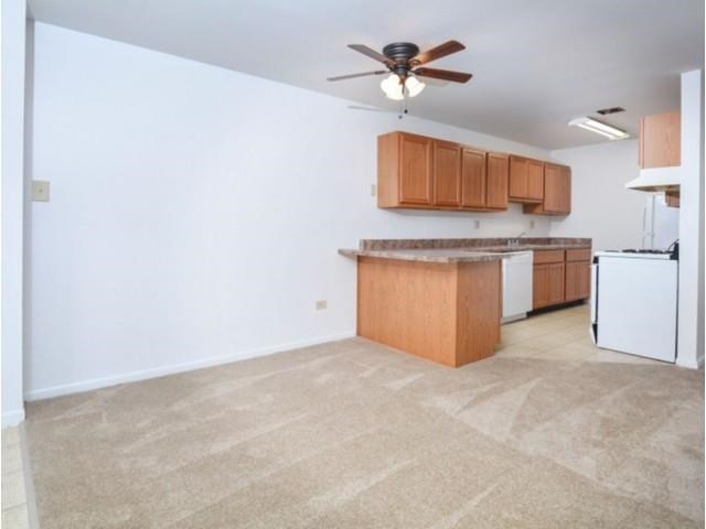 an empty kitchen with a ceiling fan and