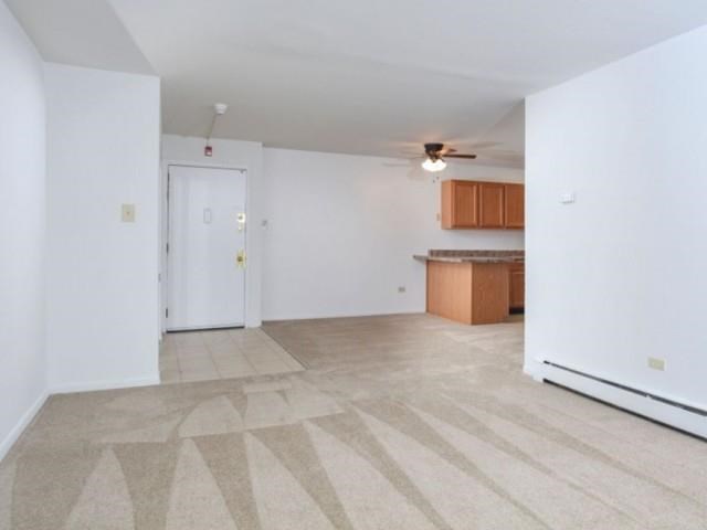 an empty living room and kitchen with a ceiling fan