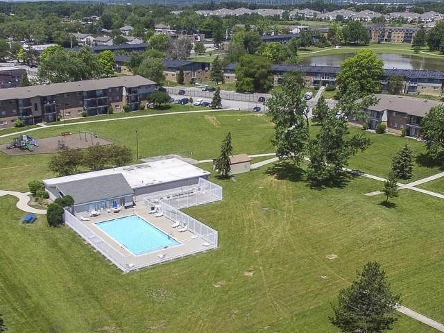 an aerial view of a pool and a building in the grass