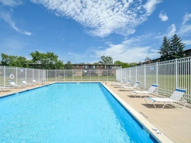 a swimming pool with chairs and a fence around it