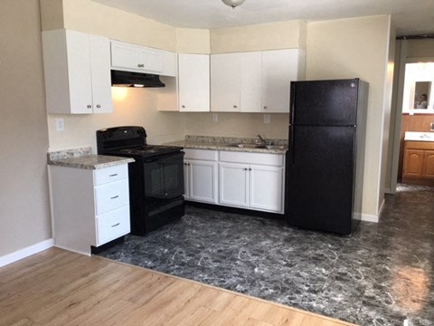 A kitchen with black appliances and white cabinets.