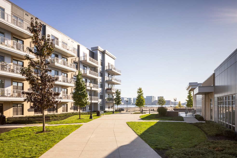 a view of an apartment building with a sidewalk and grass