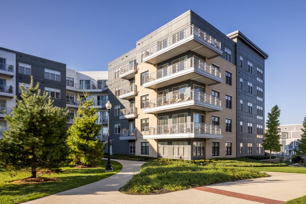 an apartment building on a sunny day with a sidewalk