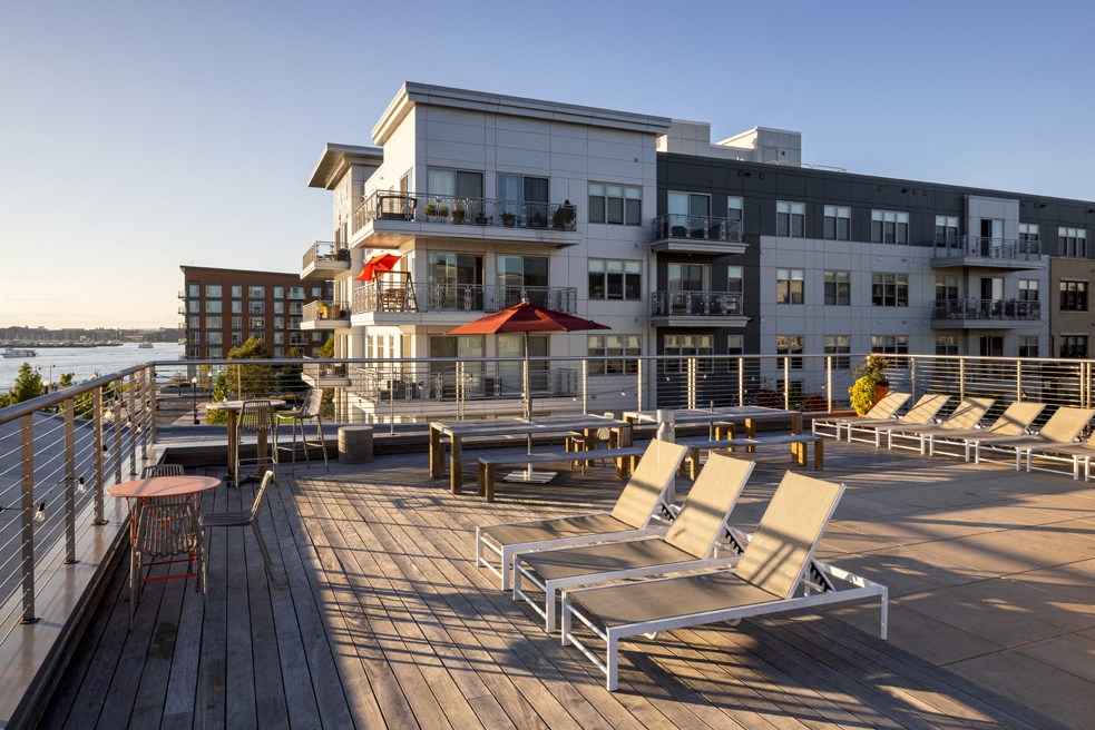 a row of lounge chairs on a deck next to a building