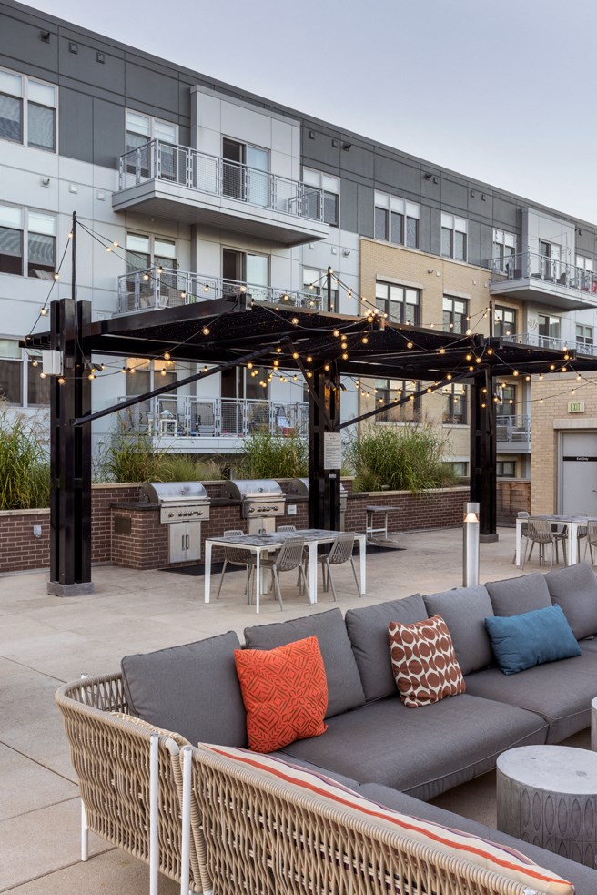 a patio with a couch and tables in front of a building