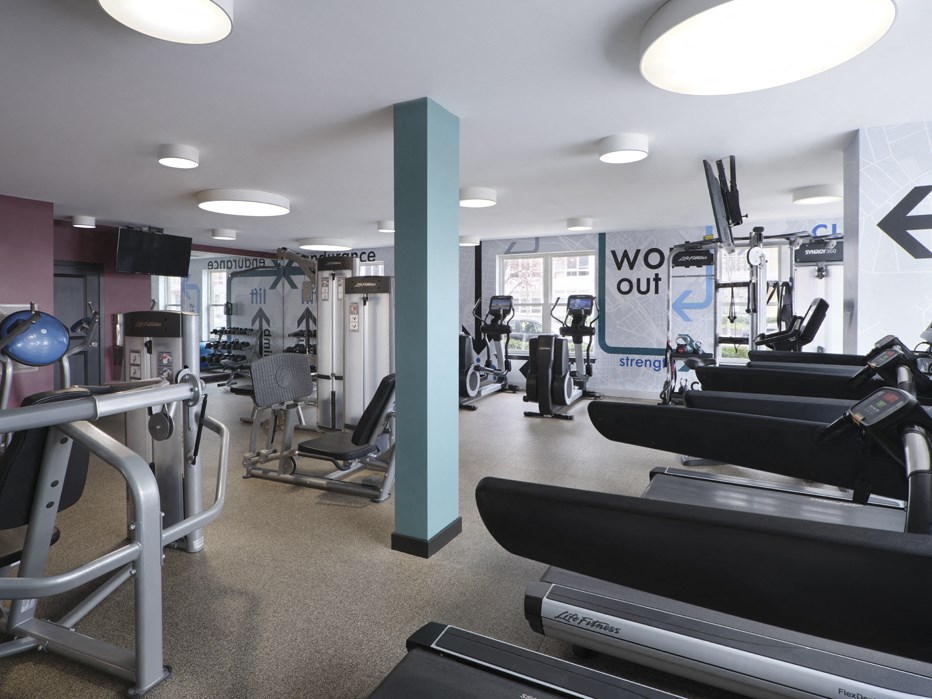 a gym with treadmills and other exercise equipment in a room with a window