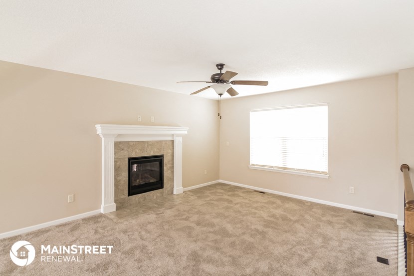 the living room with fireplace and ceiling fan