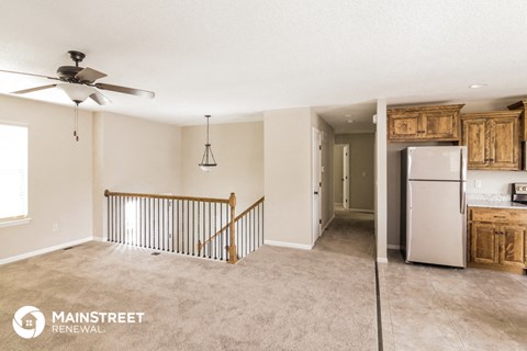 a kitchen and living room with a refrigerator and a staircase