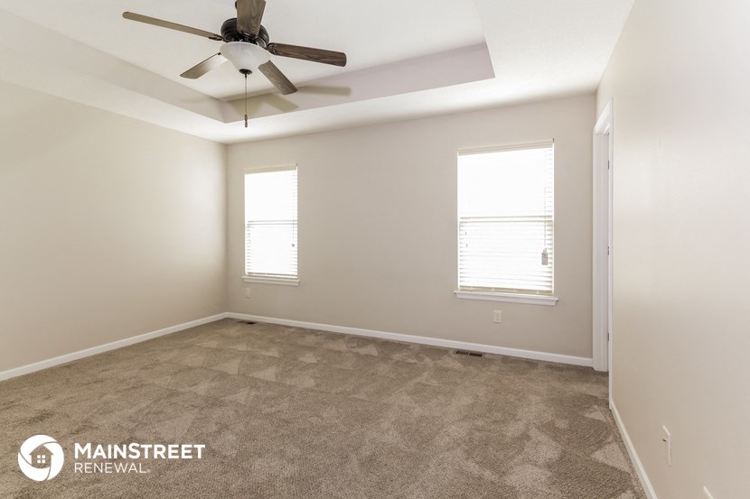 the spacious living room with ceiling fan and carpeting