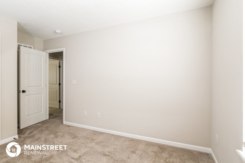 a bedroom with a white door and a carpeted floor