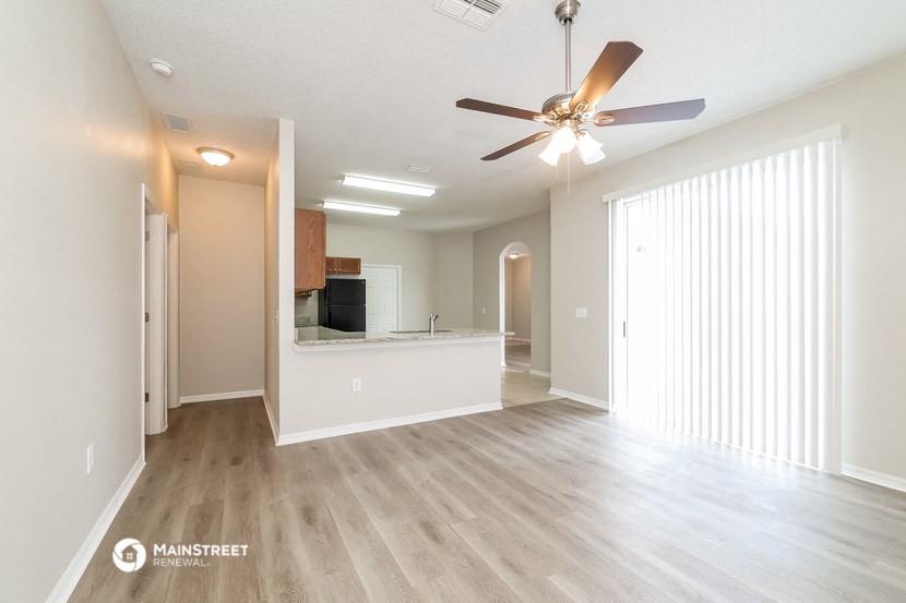 an empty living room and kitchen with a ceiling fan