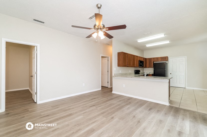 an empty living room and kitchen with a ceiling fan