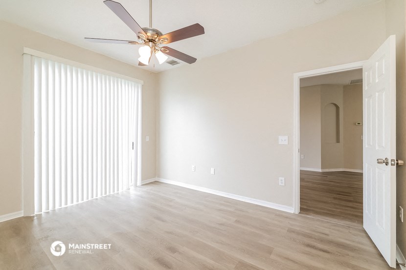 an empty living room with white walls and a ceiling fan