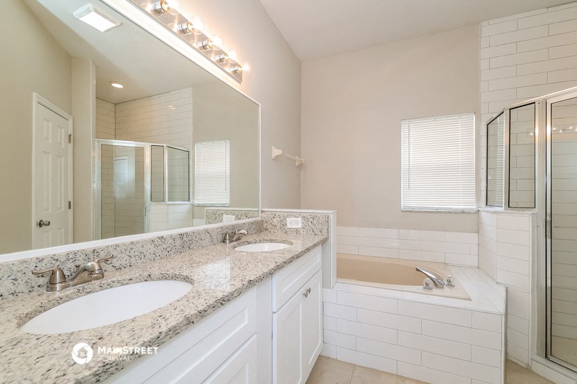 a bathroom with two sinks and a tub and a mirror