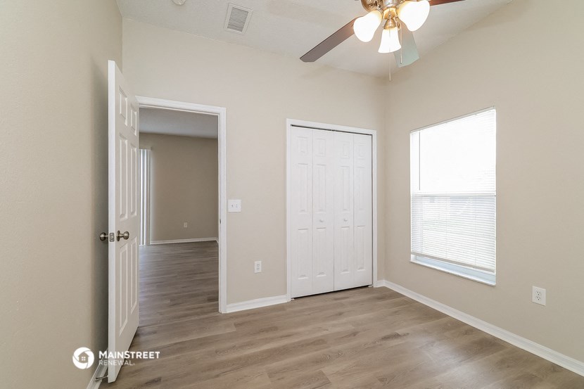 an empty living room with a ceiling fan and a window