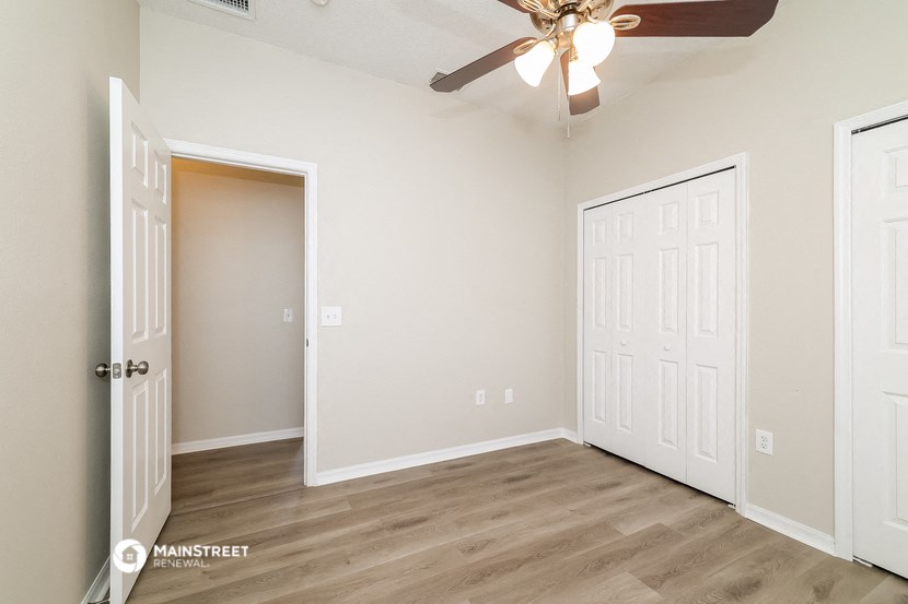 a bedroom with white doors and a ceiling fan