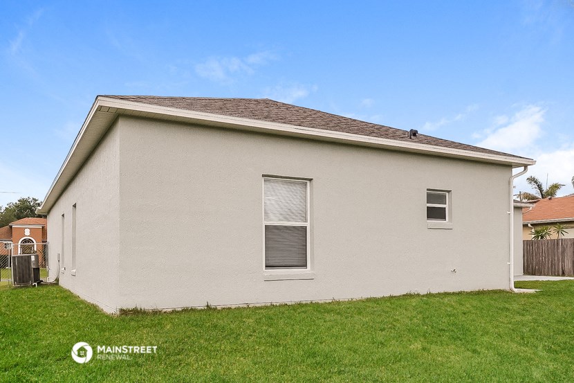 a small white house with a grassy yard and a fence