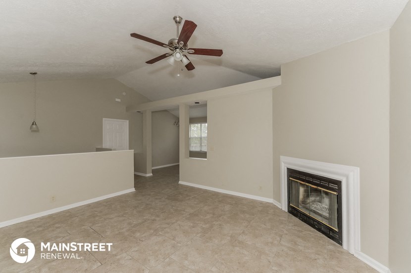 a living room with a fireplace and a ceiling fan