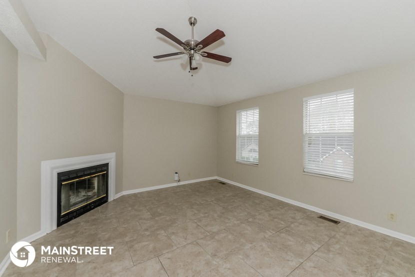 an empty living room with a fireplace and a ceiling fan